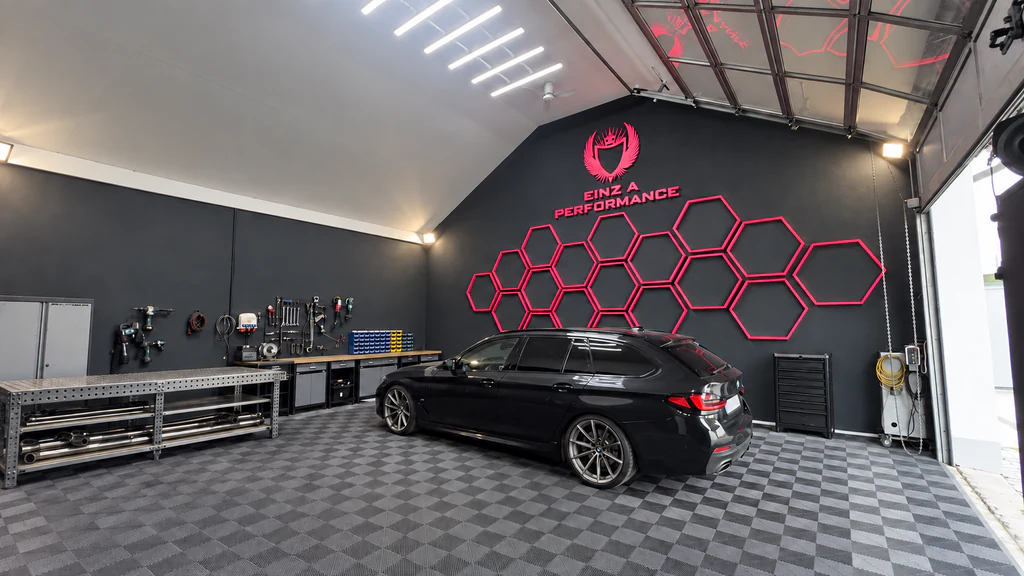 Fahrzeugwerkstatt von Einz A Performance in Olching mit schwarzem BMW und pink beleuchteter Logowand